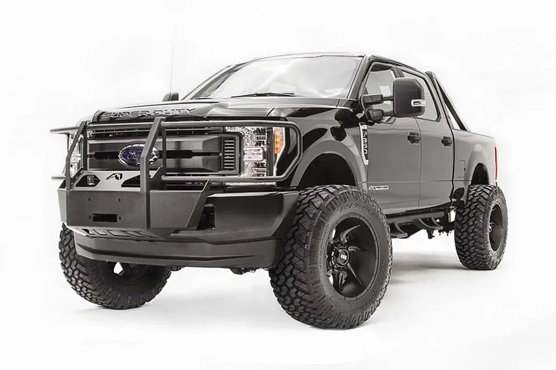 Fab Fours winch mount with full guard on a black Ford Super Duty, front driver-side three-quarter view, showing full grille guard uprights, the winch mount plate, and the factory bumper integration