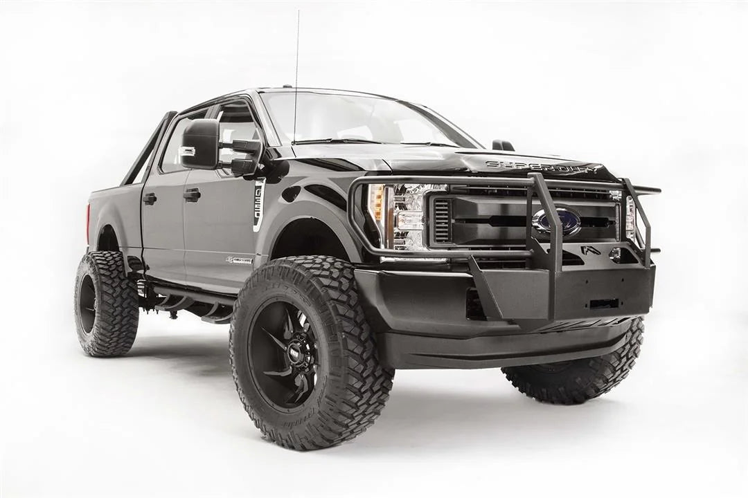 Fab Fours winch mount with full guard on a black Ford Super Duty, front passenger-side three-quarter view, showing full grille guard uprights, the winch mount plate, and the factory bumper integration