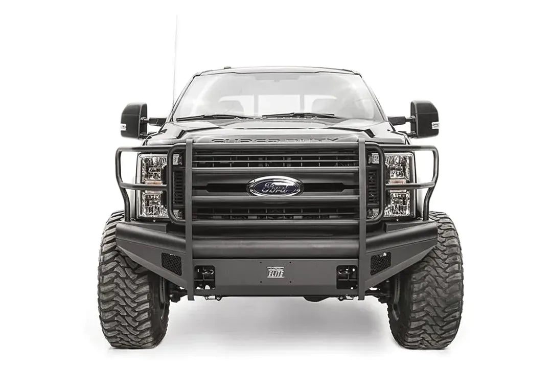 Fab Fours Black Steel Elite front bumper with full guard on a black Ford Super Duty, straight-on front view, showing full grille guard uprights and side hoops, the smooth steel face, mesh-backed side openings, and the center license plate mount