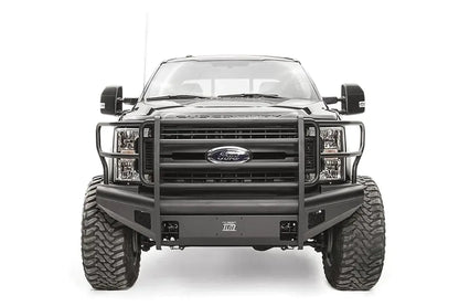 Fab Fours Black Steel Elite front bumper with full guard on a black Ford Super Duty, straight-on front view, showing full grille guard uprights and side hoops, the smooth steel face, mesh-backed side openings, and the center license plate mount