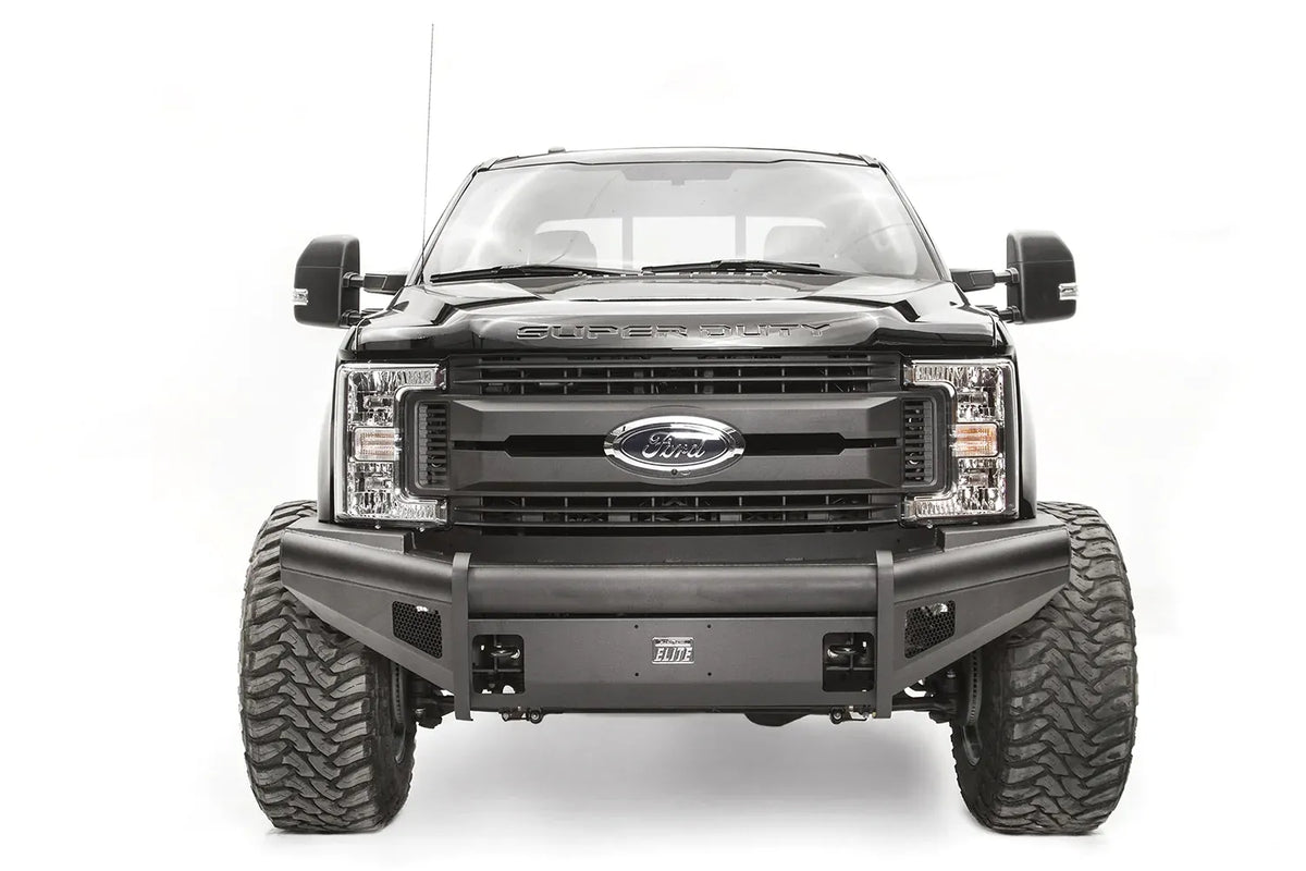 Fab Fours Black Steel Elite front bumper on a black Ford Super Duty, straight-on front view, showing the smooth steel face, mesh-backed side openings, and the center license plate mount