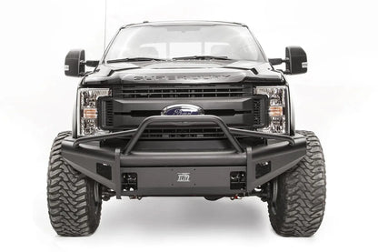 Fab Fours Black Steel Elite front bumper with pre-runner guard on a black Ford Super Duty, straight-on front view, showing the tubular pre-runner hoop, the smooth steel face, mesh-backed side openings, and the center license plate mount