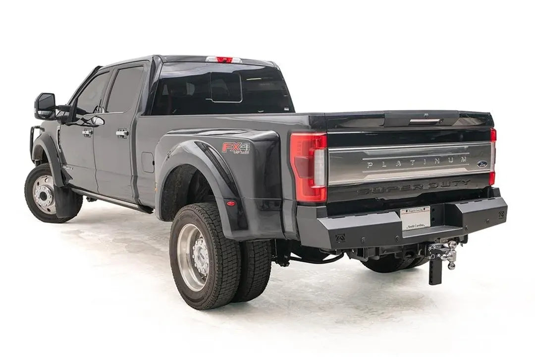 Fab Fours Red Steel rear bumper on a black Ford Super Duty Platinum dually, rear driver-side view with the flat black bumper, plate mount and adjustable ball hitch