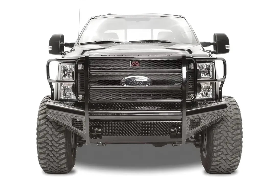 Fab Fours Black Steel front bumper with full guard on a black Ford Super Duty, straight-on front view, showing full grille guard with mesh insert, diamond-plate face panels, the center license plate mount, and angled side wings