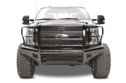Fab Fours Black Steel front bumper with full guard on a black Ford Super Duty, straight-on front view, showing full grille guard with mesh insert, diamond-plate face panels, the center license plate mount, and angled side wings