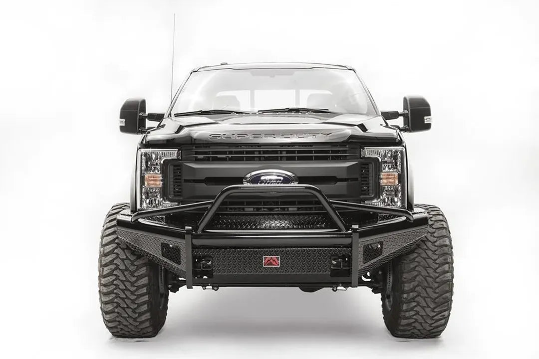 Fab Fours Black Steel front bumper with pre-runner guard on a black Ford Super Duty, straight-on front view, showing the tubular pre-runner hoop, diamond-plate face panels, the center license plate mount, and angled side wings