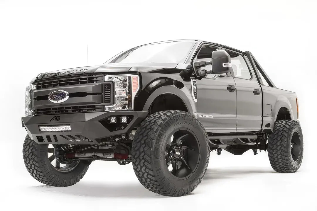 Fab Fours Vengeance front bumper on a black and gray Ford Super Duty F-250/F-350, front driver-side three-quarter view, showing the center LED light bar, cube light pods, and the open skid plate design