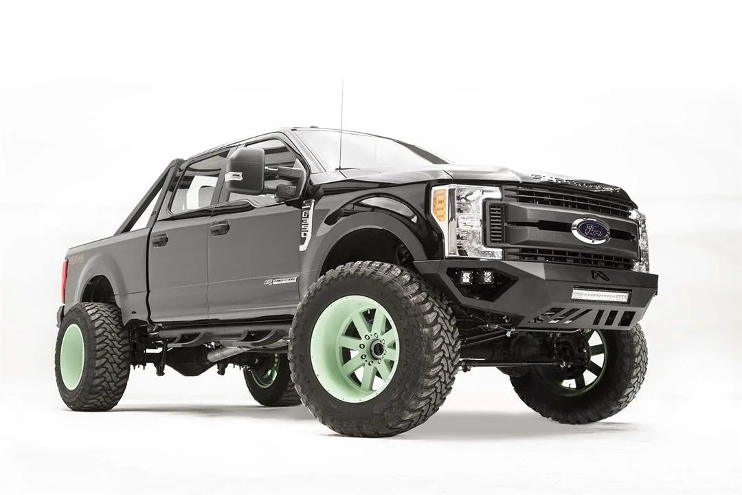 Fab Fours Vengeance front bumper on a black and gray Ford Super Duty F-250/F-350, front passenger-side three-quarter view, showing the center LED light bar, cube light pods, and the open skid plate design