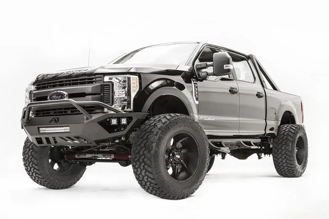 Fab Fours Vengeance front bumper with pre-runner guard on a black and gray Ford Super Duty F-250/F-350, front driver-side three-quarter view, showing the tubular pre-runner hoop, the center LED light bar, cube light pods, and the open skid plate design