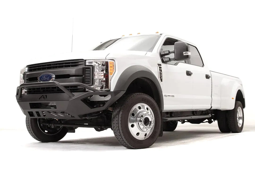 Fab Fours Vengeance front bumper with pre-runner guard on a white Ford Super Duty F-450/F-550, front driver-side three-quarter view, showing the tubular pre-runner hoop, the center LED light bar, cube light pods, and the open skid plate design
