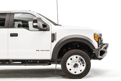 Fab Fours Vengeance front bumper with pre-runner guard on a white Ford Super Duty F-450/F-550, passenger-side profile view of the front corner, showing the tubular pre-runner hoop, the center LED light bar, cube light pods, and the open skid plate design