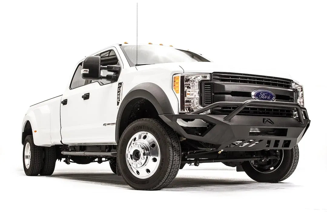 Fab Fours Vengeance front bumper with pre-runner guard on a white Ford Super Duty F-450/F-550, front passenger-side three-quarter view, showing the tubular pre-runner hoop, the center LED light bar, cube light pods, and the open skid plate design
