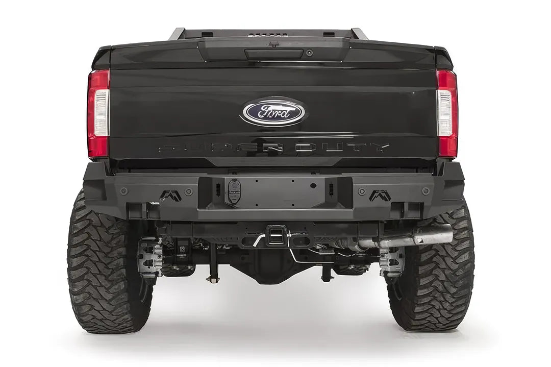 Fab Fours Premium rear bumper on a black Ford Super Duty, straight-on rear view, showing the center license plate recess, integrated light openings, and angular steel end caps