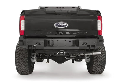 Fab Fours Premium rear bumper on a black Ford Super Duty, straight-on rear view, showing the center license plate recess, integrated light openings, and angular steel end caps