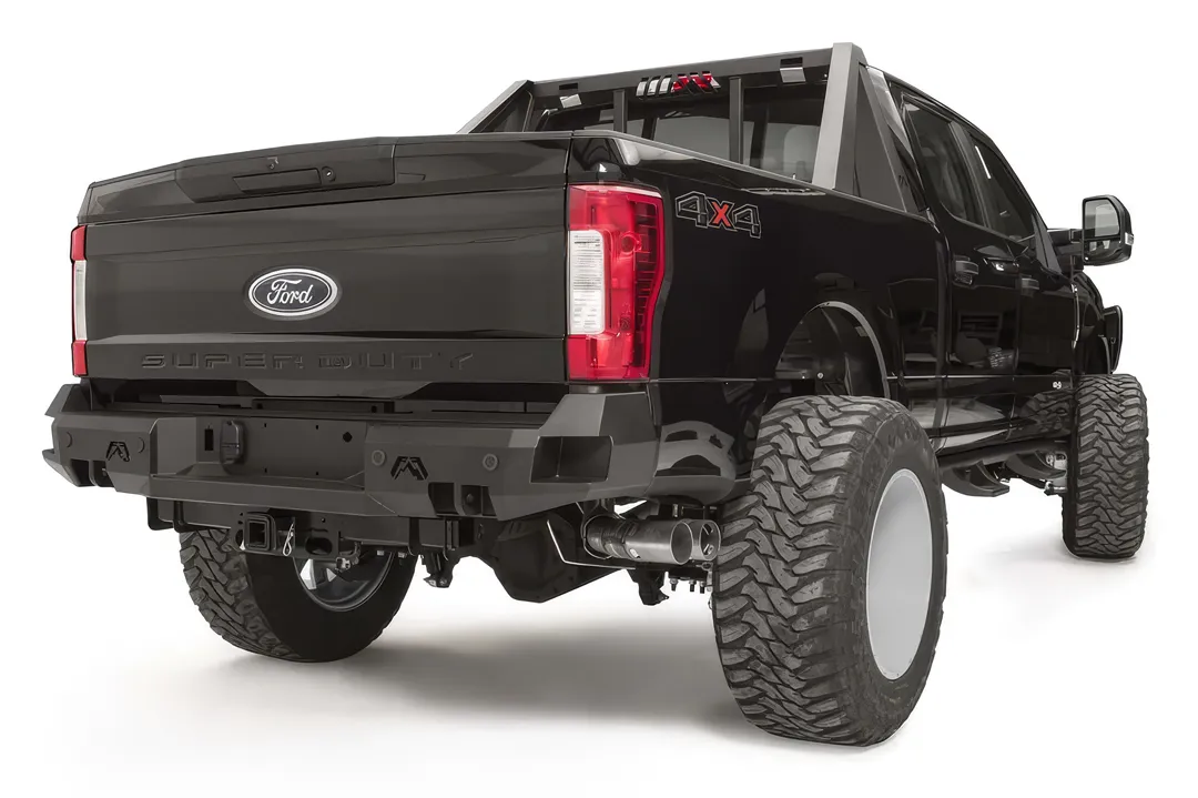 Fab Fours Premium rear bumper on a black Ford Super Duty, rear passenger-side three-quarter view, showing the center license plate recess, integrated light openings, and angular steel end caps