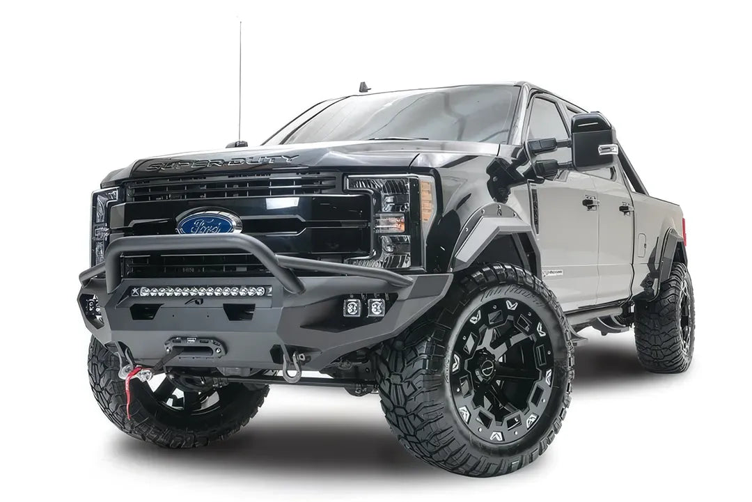 Fab Fours Matrix front bumper with pre-runner guard on a black Ford Super Duty F-250/F-350, front driver-side three-quarter view, showing the tubular pre-runner hoop, the center LED light bar, cube light pods, and the integrated winch with shackle mounts