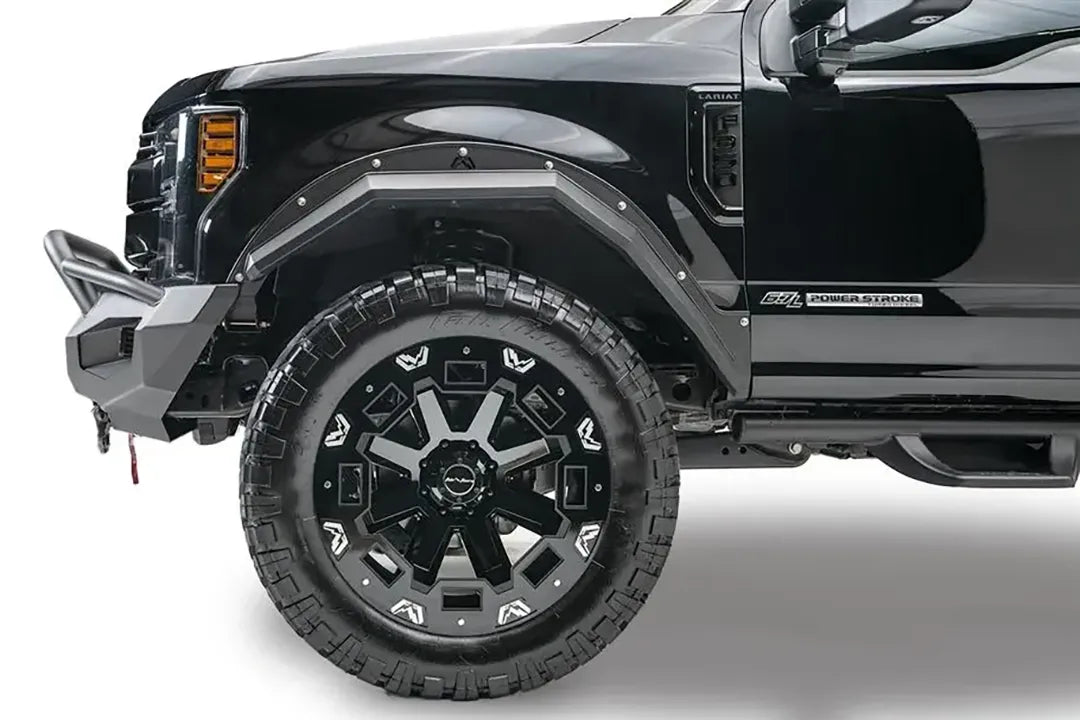 Fab Fours Matrix front bumper with pre-runner guard on a black Ford Super Duty F-250/F-350, driver-side profile view of the front corner, showing the tubular pre-runner hoop, the center LED light bar, cube light pods, and the integrated winch with shackle mounts
