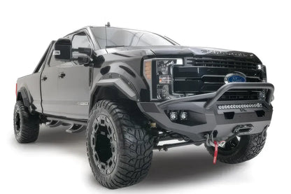 Fab Fours Matrix front bumper with pre-runner guard on a black Ford Super Duty F-250/F-350, front passenger-side three-quarter view, showing the tubular pre-runner hoop, the center LED light bar, cube light pods, and the integrated winch with shackle mounts