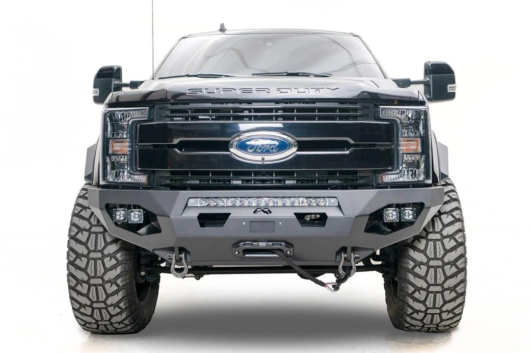 Fab Fours Matrix front bumper on a black Ford Super Duty F-250/F-350, straight-on front view, showing the center LED light bar, cube light pods, and the integrated winch with shackle mounts