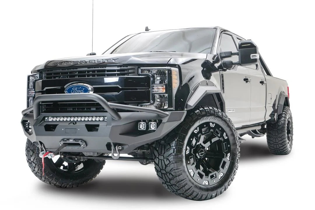 Fab Fours Matrix front bumper with pre-runner guard on a black Ford Super Duty F-250/F-350, front driver-side three-quarter view, showing the tubular pre-runner hoop, the center LED light bar, cube light pods, and the integrated winch with shackle mounts