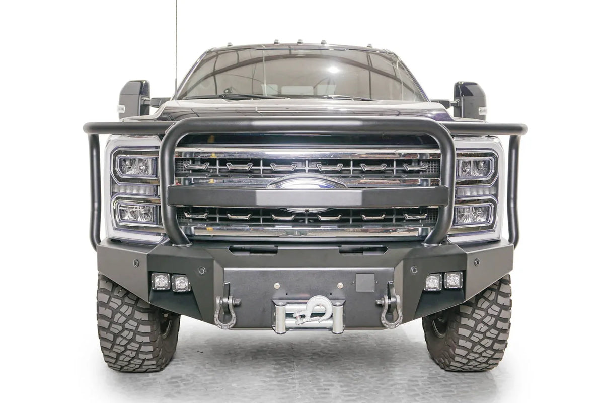 Fab Fours Premium Winch front bumper with full guard on a blue and gray two-tone Ford Super Duty F-250/F-350, straight-on front view, showing full grille guard hoops, the center winch plate with fairlead, LED light pods, and D-ring shackle mounts