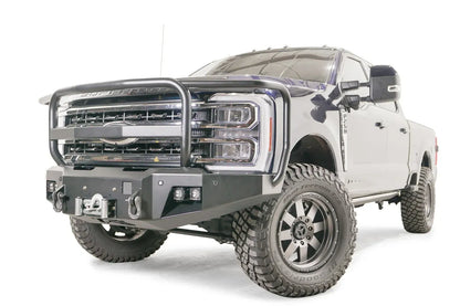 Fab Fours Premium Winch front bumper with full guard on a blue and gray two-tone Ford Super Duty F-250/F-350, front driver-side three-quarter view, showing full grille guard hoops, the center winch plate with fairlead, LED light pods, and D-ring shackle mounts