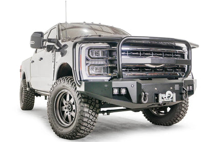 Fab Fours Premium Winch front bumper with full guard on a blue and gray two-tone Ford Super Duty F-250/F-350, front passenger-side three-quarter view, showing full grille guard hoops, the center winch plate with fairlead, LED light pods, and D-ring shackle mounts