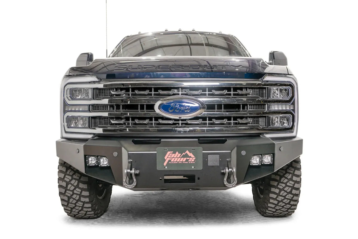 Fab Fours Premium Winch front bumper on a blue and gray two-tone Ford Super Duty F-250/F-350, straight-on front view, showing the center winch plate with fairlead, LED light pods, and D-ring shackle mounts