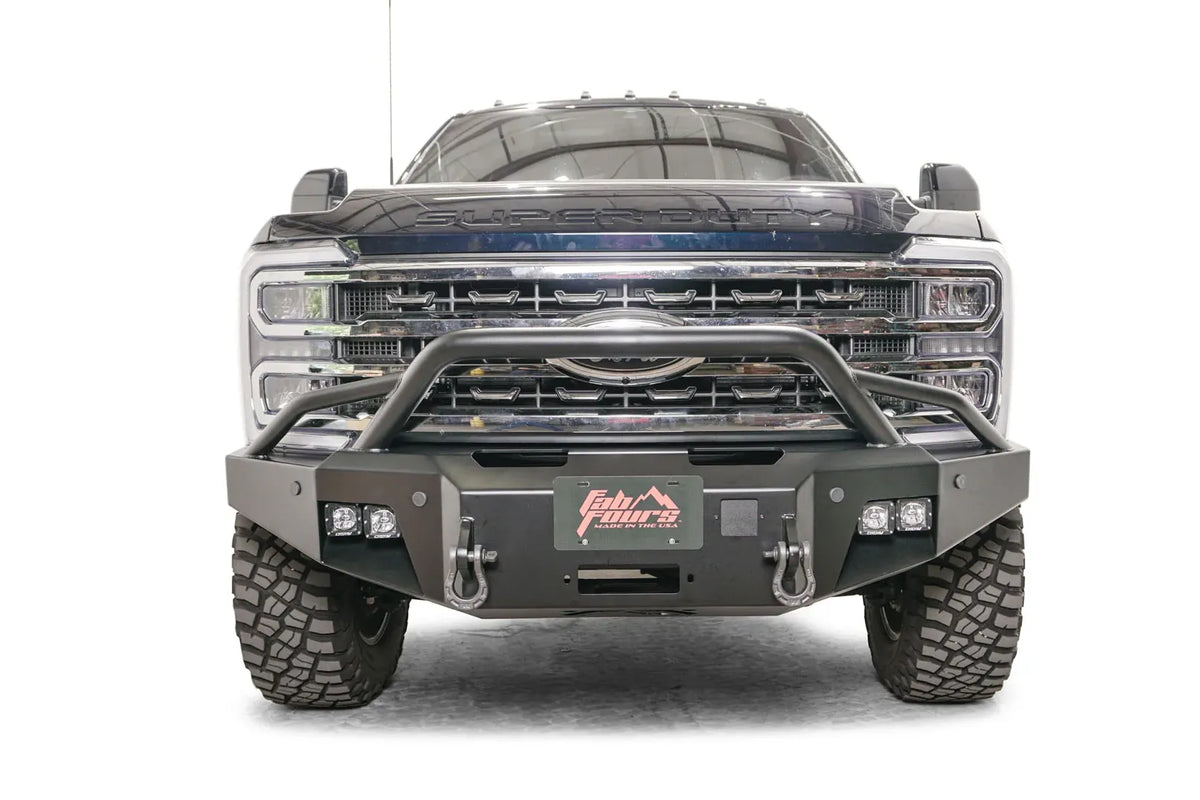 Fab Fours Premium Winch front bumper with pre-runner guard on a blue and gray two-tone Ford Super Duty F-250/F-350, straight-on front view, showing the tubular pre-runner hoop, the center winch plate with fairlead, LED light pods, and D-ring shackle mounts