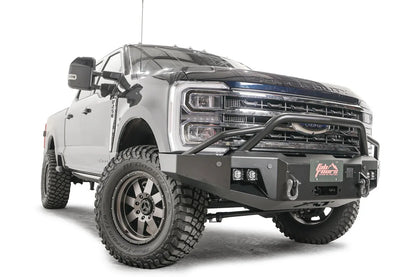 Fab Fours Premium Winch front bumper with pre-runner guard on a blue and gray two-tone Ford Super Duty F-250/F-350, front passenger-side three-quarter view, showing the tubular pre-runner hoop, the center winch plate with fairlead, LED light pods, and D-ring shackle mounts