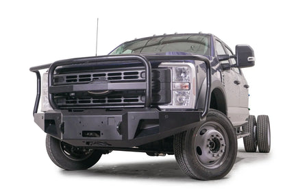 Fab Fours Premium Winch front bumper with full guard on a blue and gray two-tone Ford Super Duty F-450/F-550, front driver-side three-quarter view, showing full grille guard hoops, the center winch plate, angular end caps, and recessed light openings