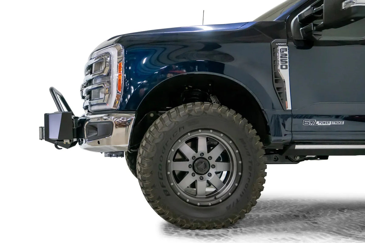 Fab Fours winch mount with pre-runner hoop on a dark blue Ford Super Duty F-250/F-350, driver-side profile view of the front corner, showing the tubular pre-runner hoop, the winch mount plate with fairlead and the factory bumper integration
