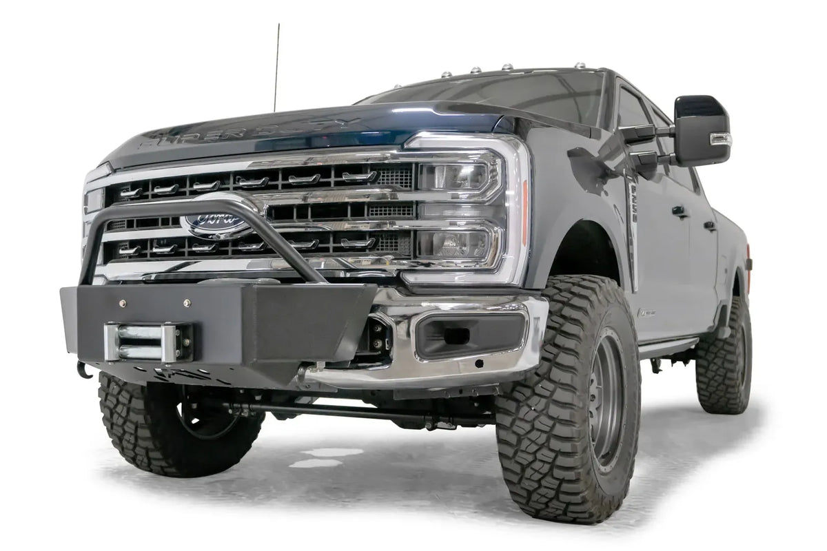 Fab Fours winch mount with pre-runner hoop on a blue and gray two-tone Ford Super Duty F-250/F-350, front driver-side three-quarter view, showing the tubular pre-runner hoop, the winch mount plate with fairlead and the factory bumper integration