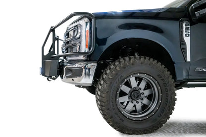Fab Fours winch mount with full guard on a dark blue Ford Super Duty F-250/F-350, driver-side profile view of the front corner, showing full grille guard uprights and hoops, the winch mount plate with fairlead and the factory bumper integration