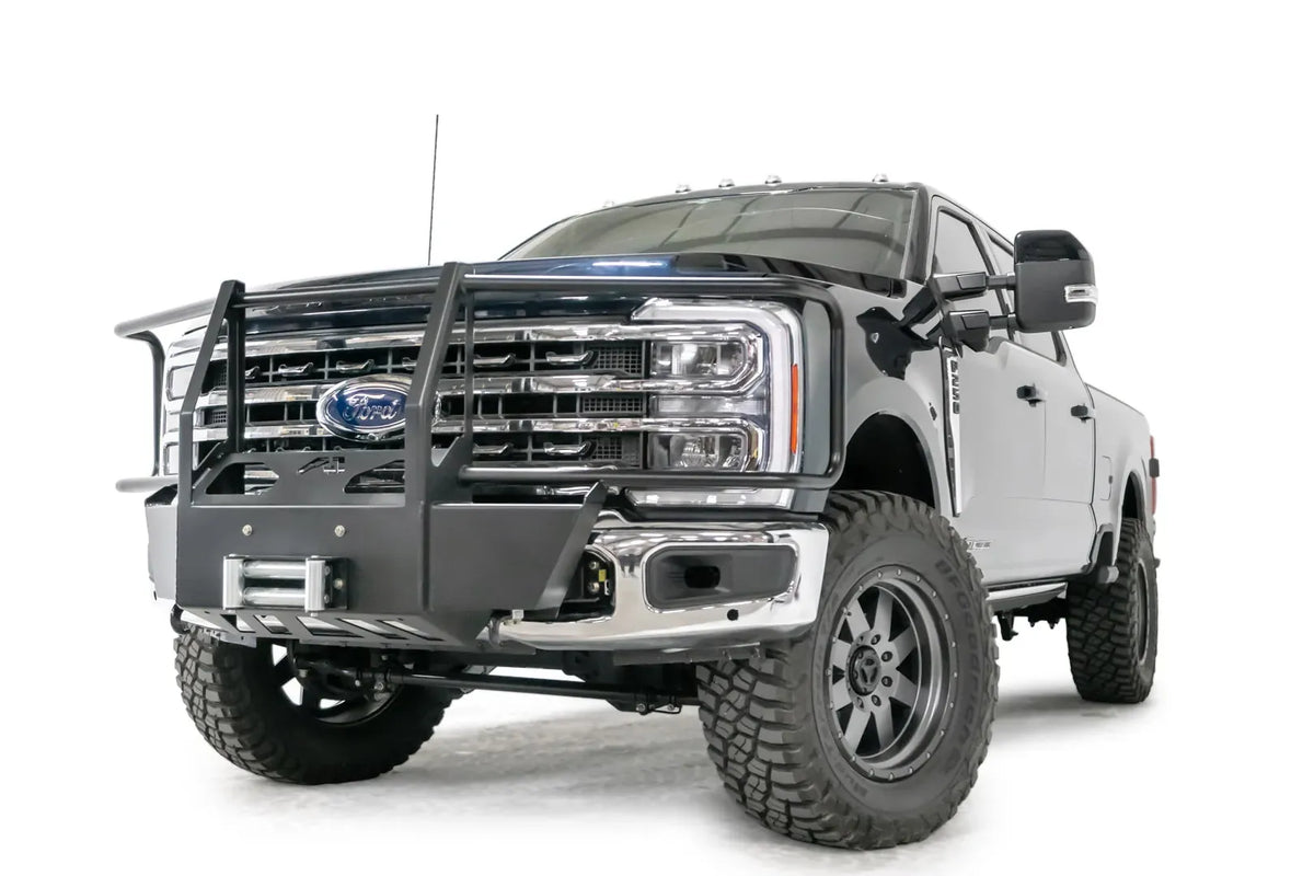 Fab Fours winch mount with full guard on a blue and gray two-tone Ford Super Duty F-250/F-350, front driver-side three-quarter view, showing full grille guard uprights and hoops, the winch mount plate with fairlead and the factory bumper integration