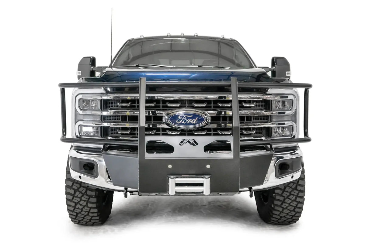 Fab Fours winch mount with full guard on a blue and gray two-tone Ford Super Duty F-250/F-350, straight-on front view, showing full grille guard uprights and hoops, the winch mount plate with fairlead and the factory bumper integration