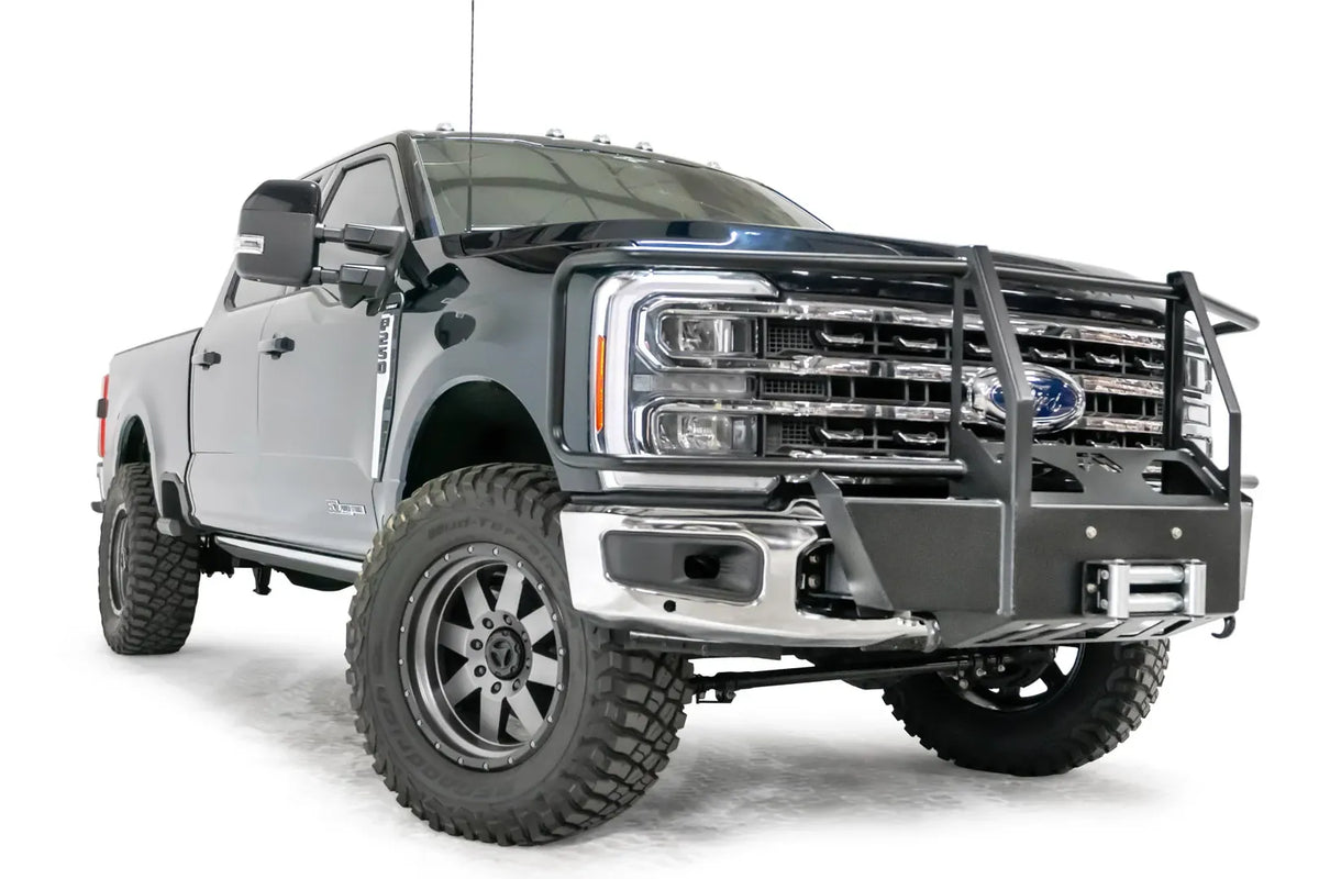 Fab Fours winch mount with full guard on a blue and gray two-tone Ford Super Duty F-250/F-350, front passenger-side three-quarter view, showing full grille guard uprights and hoops, the winch mount plate with fairlead and the factory bumper integration