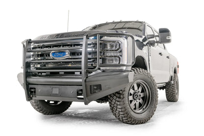 Fab Fours Black Steel Elite front bumper with full guard on a blue and gray two-tone Ford Super Duty, front driver-side three-quarter view, showing full grille guard uprights and side hoops, the smooth steel face, mesh-backed side openings, and the center sensor/plate mount
