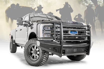 Fab Fours Black Steel Elite front bumper with full guard on a blue and gray two-tone Ford Super Duty, front passenger-side three-quarter view outdoors, showing full grille guard uprights and side hoops, the smooth steel face, mesh-backed side openings, and the center sensor/plate mount