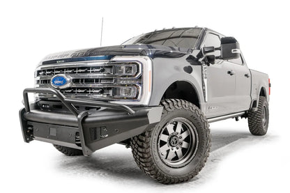 Fab Fours Black Steel Elite front bumper with pre-runner guard on a blue and gray two-tone Ford Super Duty, front driver-side three-quarter view, showing the tubular pre-runner hoop, the smooth steel face, mesh-backed side openings, and the center sensor/plate mount