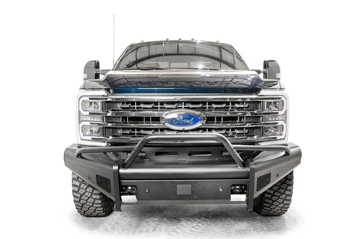Fab Fours Black Steel Elite front bumper with pre-runner guard on a blue and gray two-tone Ford Super Duty, straight-on front view, showing the tubular pre-runner hoop, the smooth steel face, mesh-backed side openings, and the center sensor/plate mount