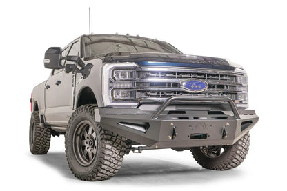 Fab Fours Red Steel front bumper with pre-runner guard on a blue and gray two-tone Ford Super Duty, front passenger-side three-quarter view, showing the tubular pre-runner hoop, the center winch mount plate, and angular steel wings