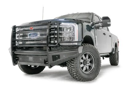 Fab Fours Black Steel front bumper with full guard on a blue and gray two-tone Ford Super Duty, front driver-side three-quarter view, showing full grille guard with mesh insert, diamond-plate face panels, the center sensor/plate mount, and angled side wings