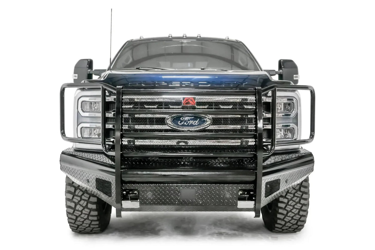 Fab Fours Black Steel front bumper with full guard on a blue and gray two-tone Ford Super Duty, straight-on front view, showing full grille guard with mesh insert, diamond-plate face panels, the center sensor/plate mount, and angled side wings