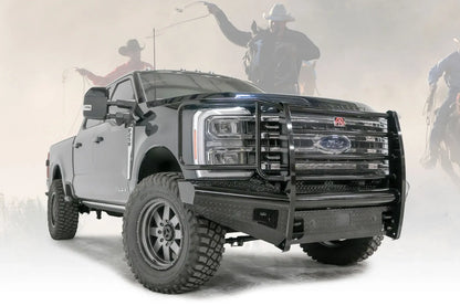 Fab Fours Black Steel front bumper with full guard on a blue and gray two-tone Ford Super Duty, front passenger-side three-quarter view outdoors, showing full grille guard with mesh insert, diamond-plate face panels, the center sensor/plate mount, and angled side wings