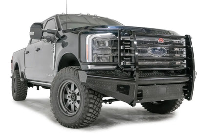 Fab Fours Black Steel front bumper with full guard on a blue and gray two-tone Ford Super Duty, front passenger-side three-quarter view, showing full grille guard with mesh insert, diamond-plate face panels, the center sensor/plate mount, and angled side wings