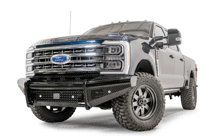 Fab Fours Black Steel front bumper on a blue and gray two-tone Ford Super Duty, front driver-side three-quarter view, showing diamond-plate face panels, the center sensor/plate mount, and angled side wings