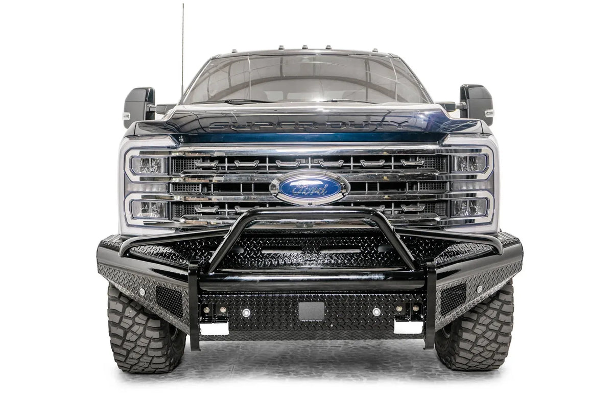 Fab Fours Black Steel front bumper with pre-runner guard on a blue and gray two-tone Ford Super Duty, straight-on front view, showing the tubular pre-runner hoop, diamond-plate face panels, the center sensor/plate mount, and angled side wings