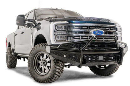 Fab Fours Black Steel front bumper with pre-runner guard on a blue and gray two-tone Ford Super Duty, front passenger-side three-quarter view, showing the tubular pre-runner hoop, diamond-plate face panels, the center sensor/plate mount, and angled side wings