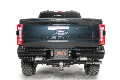 Fab Fours Black Steel rear bumper on a gray and dark blue two-tone Ford Super Duty, straight-on rear view, showing the diamond-plate face, center license plate pocket and twin LED pod lights